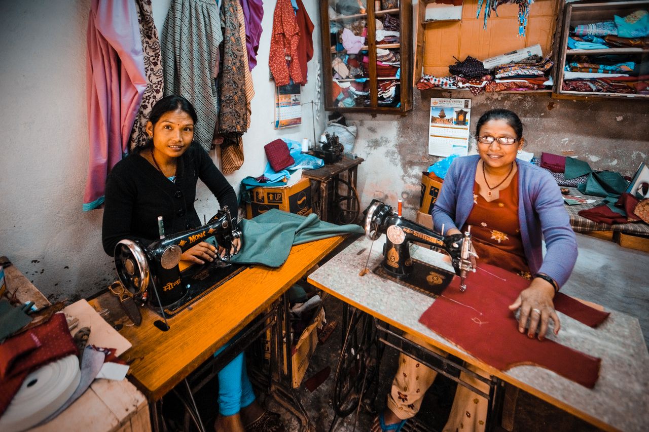 Two women dressmakers working with sewing machines in a vibrant workshop setting.