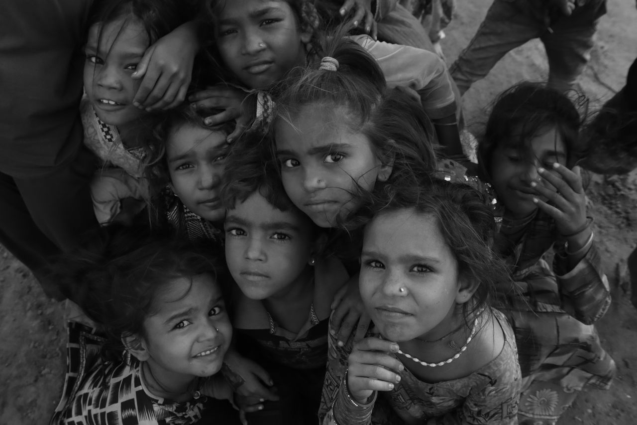 An engaging black and white photo capturing a group of South Asian children looking upwards.